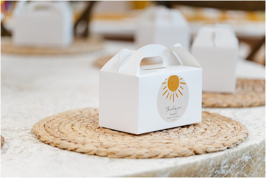 Sunny baby shower setup at Eagan Community Center with soft yellow tones, natural wood chairs, and floral arrangements in baskets.