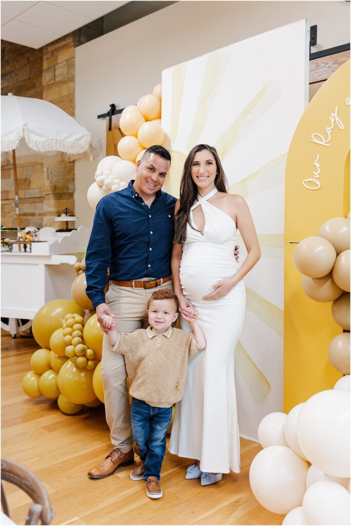 Sunny baby shower setup at Eagan Community Center with soft yellow tones, natural wood chairs, and floral arrangements in baskets.