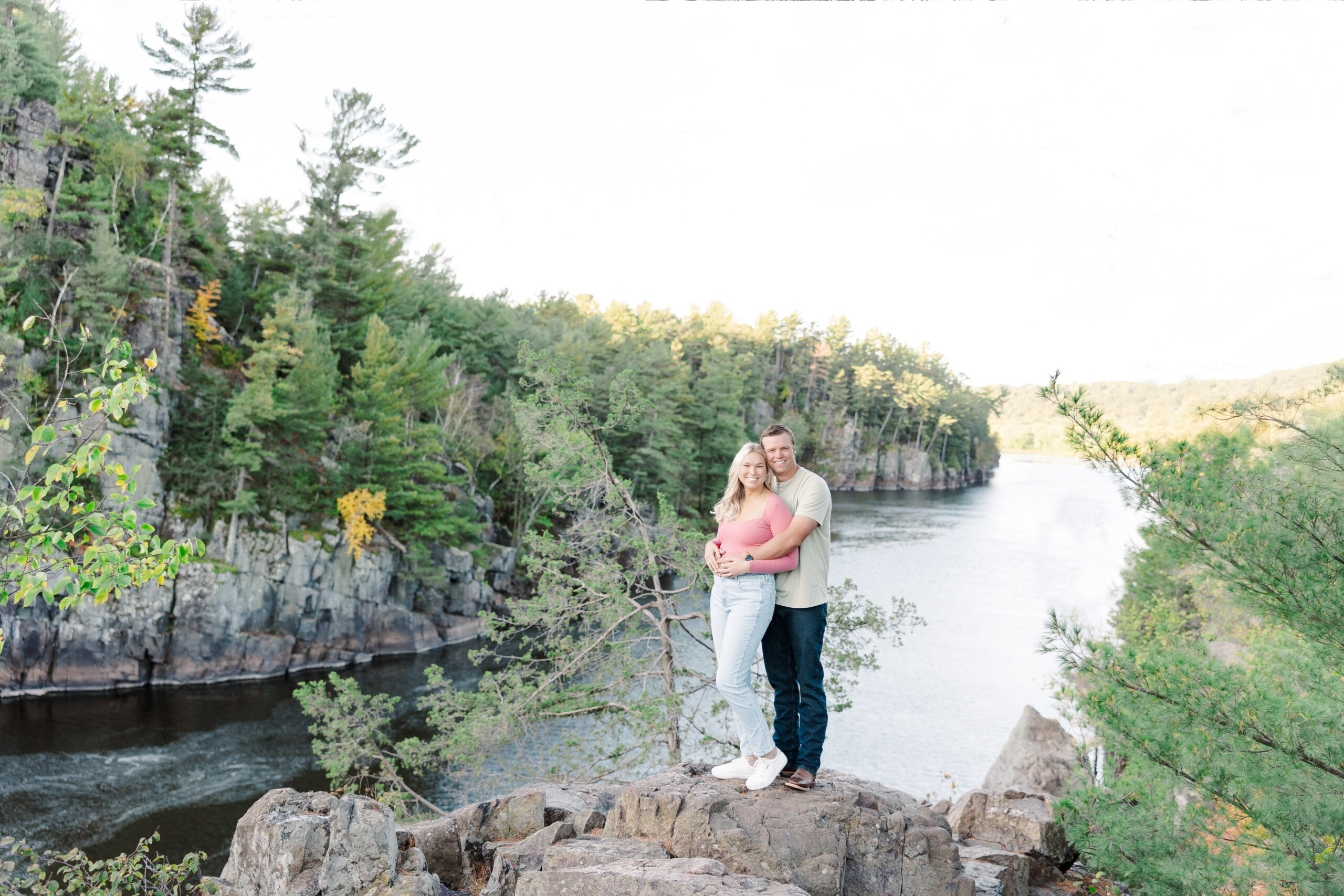 Engaged couple Kylee and Jake embrace at sunrise along the scenic Pothole Trail at Interstate State Park during their light and airy engagement session.